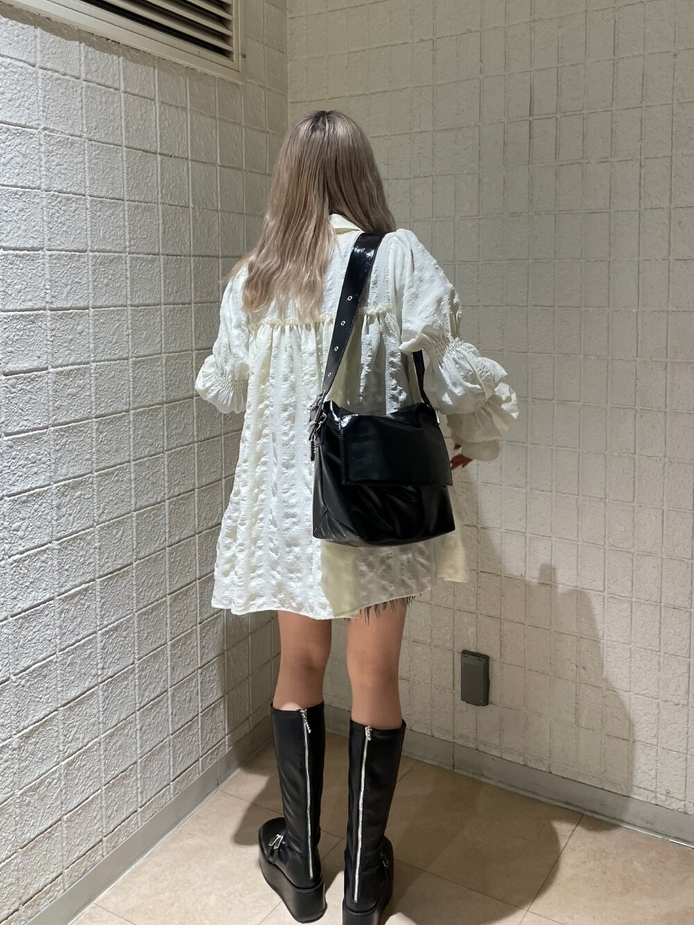 ブラック系のデニムパンツ、ホワイト系のシャツ/ブラウス、ブラック系のブーツを着用したレディースの冬コーディネートの3枚目の写真