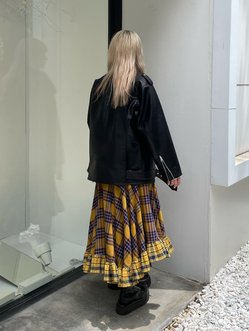 イエロー系のスカート、ブラック系のライダースジャケット、ホワイト系のTシャツ/カットソーを着用したレディースの秋コーディネートの3枚目の写真
