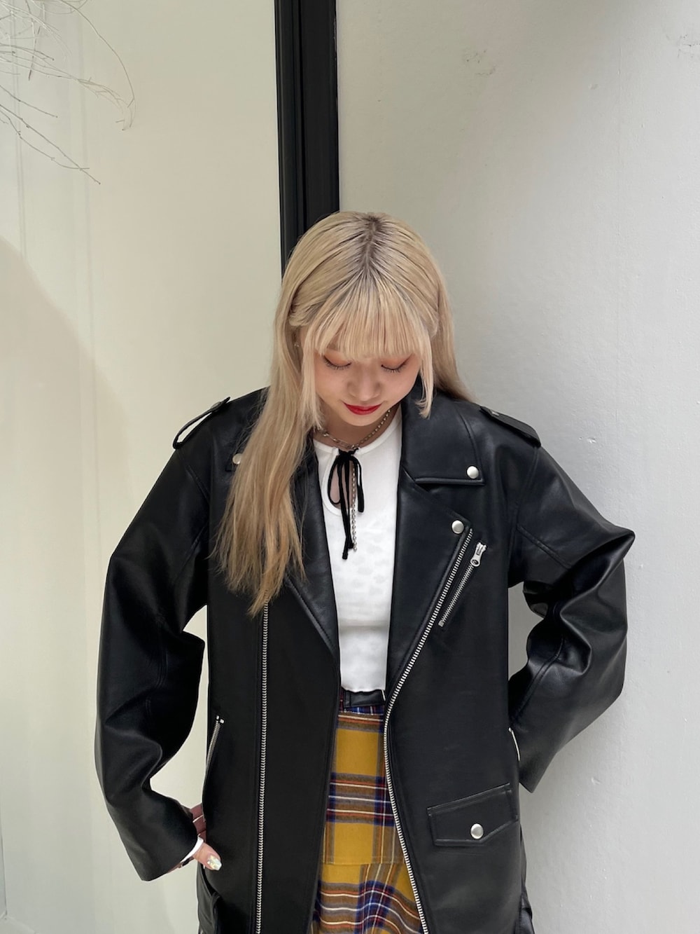 イエロー系のスカート、ブラック系のライダースジャケット、ホワイト系のTシャツ/カットソーを着用したレディースの秋コーディネートの4枚目の写真