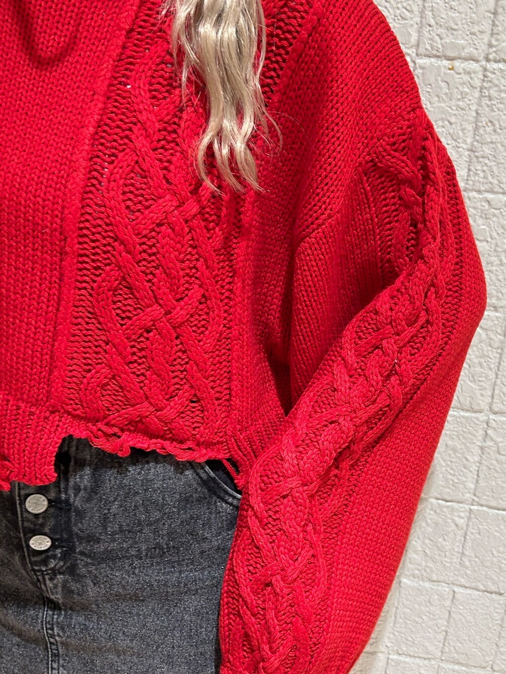 レッド系のニット/セーター、ブラック系のデニムパンツ、ブラック系のブーツを着用したレディースの冬コーディネートの5枚目の写真