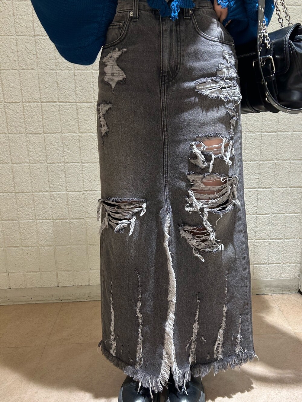 ブラック系のデニムスカート、ブルー系のニット/セーター、ブラック系のブーツを着用したレディースの冬コーディネートの7枚目の写真