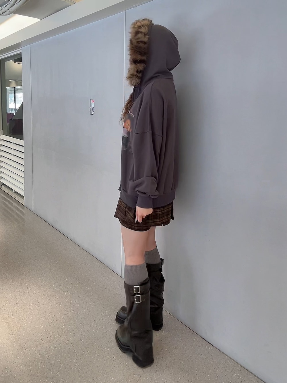 ブラウン系のスカート、ブラック系のパーカー、ブラック系のブーツを着用したレディースの秋コーディネートの3枚目の写真