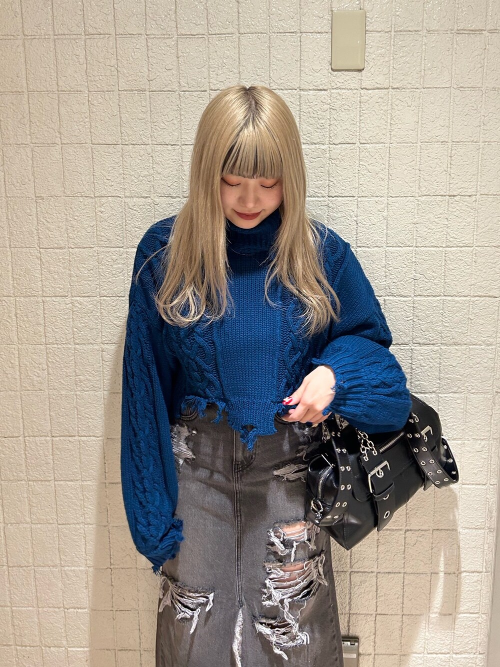 ブラック系のデニムスカート、ブルー系のニット/セーター、ブラック系のブーツを着用したレディースの冬コーディネートの4枚目の写真