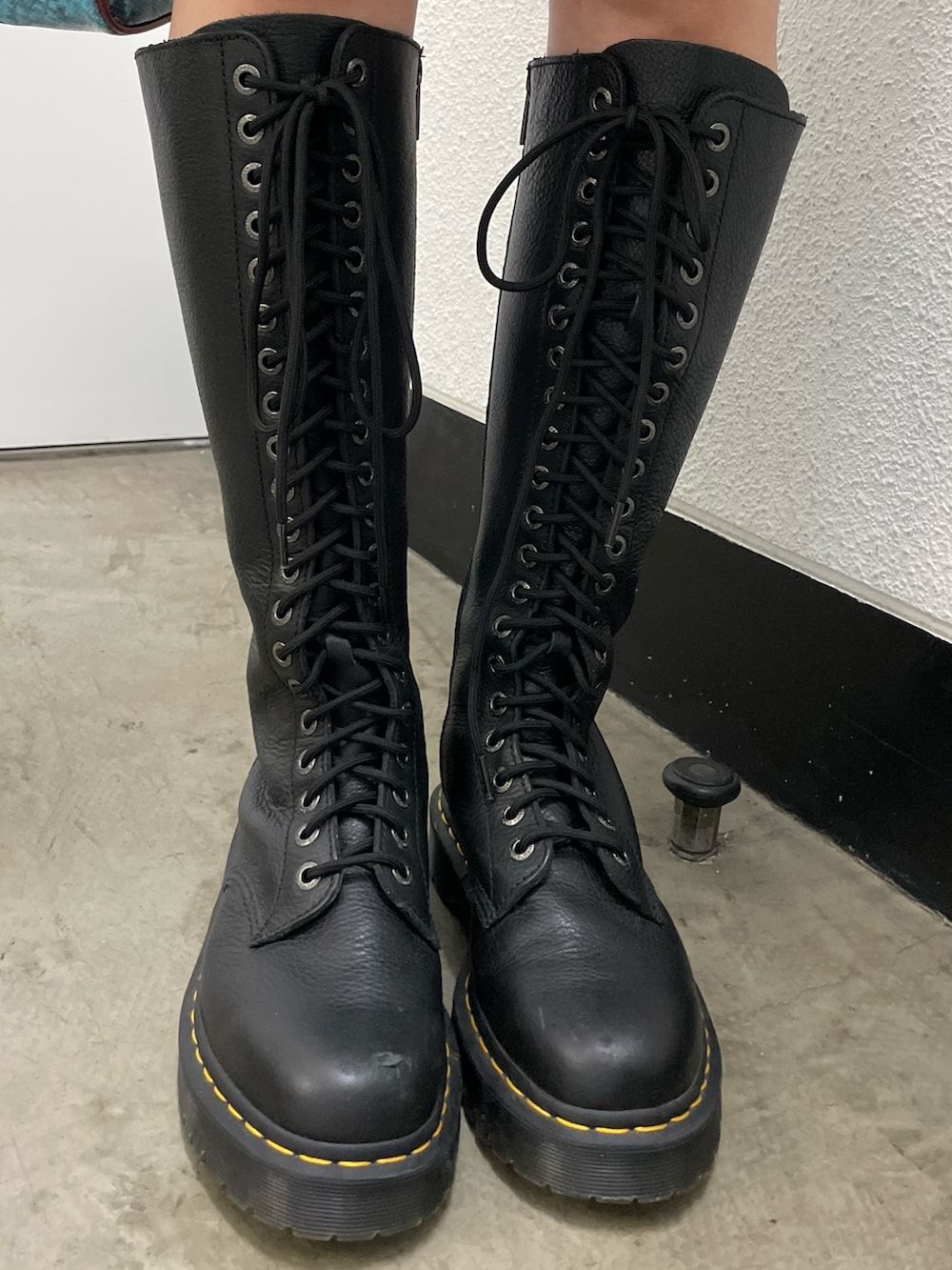 ブラック系のワンピース、ブラック系のブーツ、ブルー系のハンドバッグを着用したレディースの春コーディネートの6枚目の写真