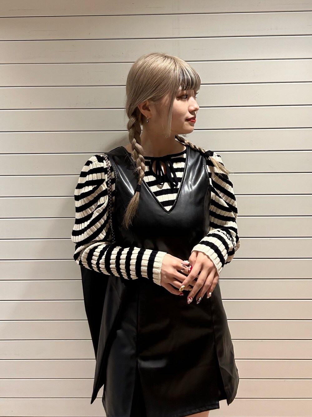 ホワイト系のニット/セーター、ブラック系のハンドバッグ、ブラック系のジャンパースカートを着用したレディースの冬コーディネートの5枚目の写真