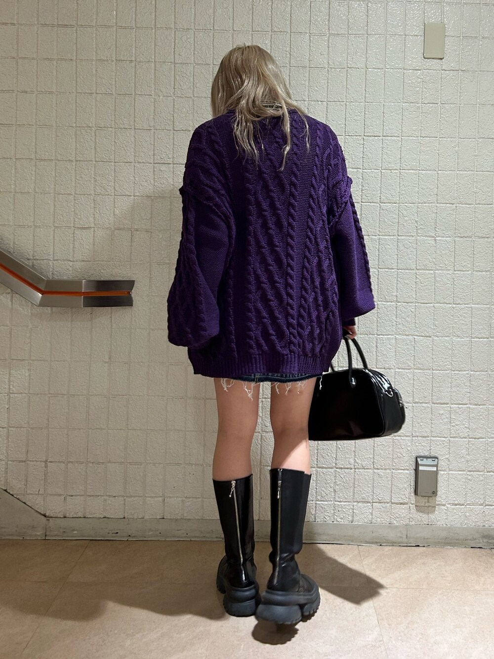 ブラック系のボストンバッグ、ブラック系のブーツ、パープル系のニット/セーターを着用したレディースの秋コーディネートの2枚目の写真