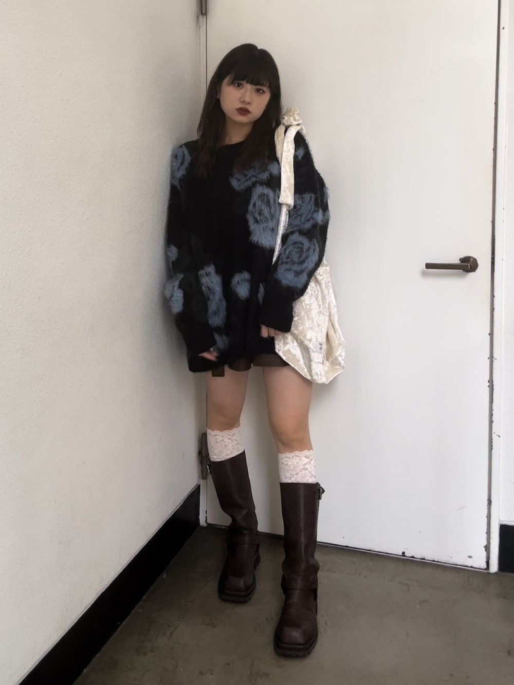 ホワイト系のトートバッグ、ブラック系のニット/セーター、ブラウン系のスカートを着用したレディースの秋コーディネートの2枚目の写真