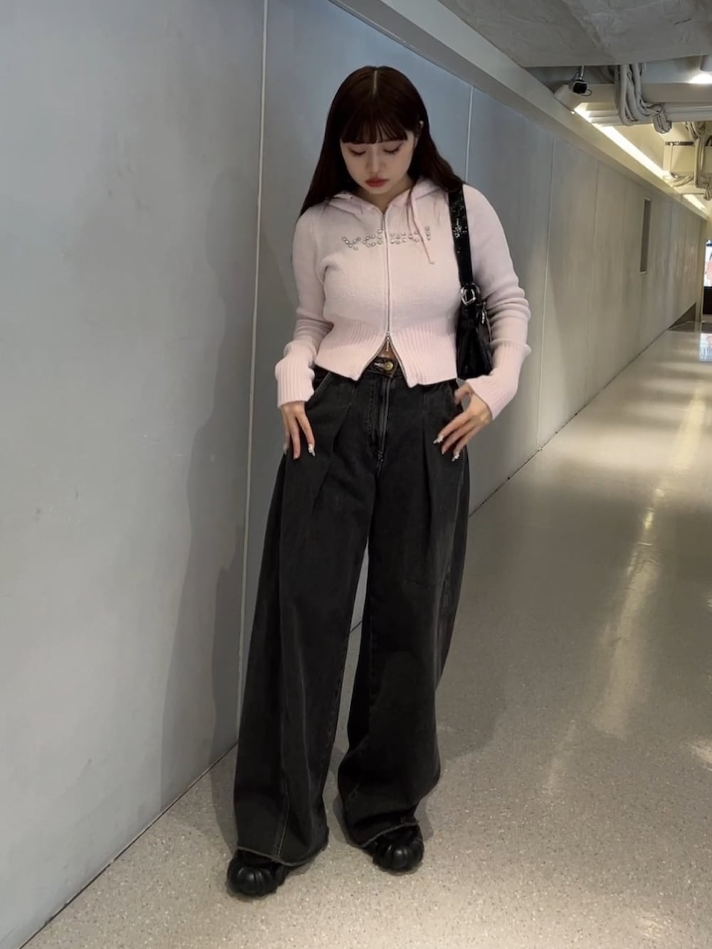 ピンク系のパーカー、ブラック系のデニムパンツを着用したレディースの冬コーディネートの2枚目の写真