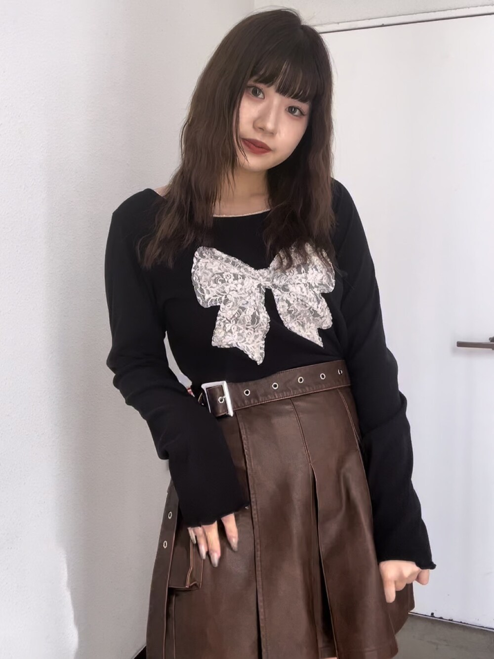 ブラック系のTシャツ/カットソー、ブラウン系のスカート、ブラウン系のブーツを着用したレディースの秋コーディネートの4枚目の写真