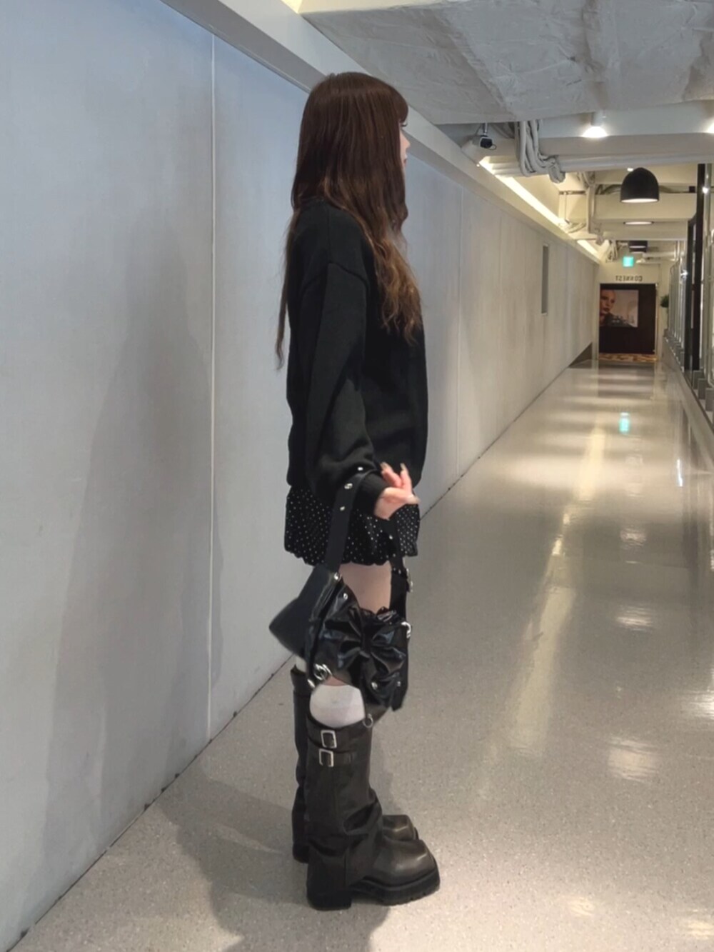 ブラック系のブーツ、ブラック系のスカート、ブラック系のショルダーバッグを着用したレディースの秋コーディネートの3枚目の写真