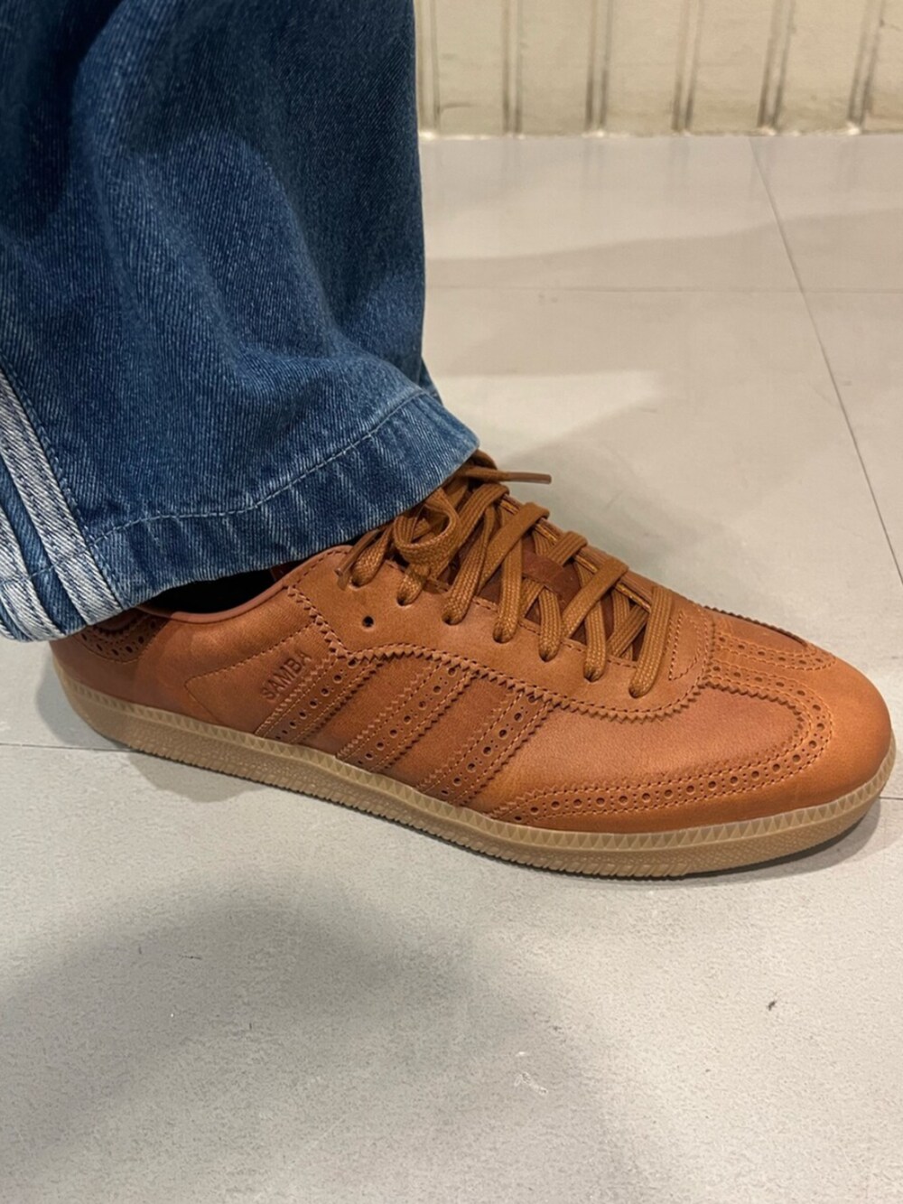 ブルー系のデニムパンツ、レッド系のシューズを着用したメンズの春コーディネートの4枚目の写真