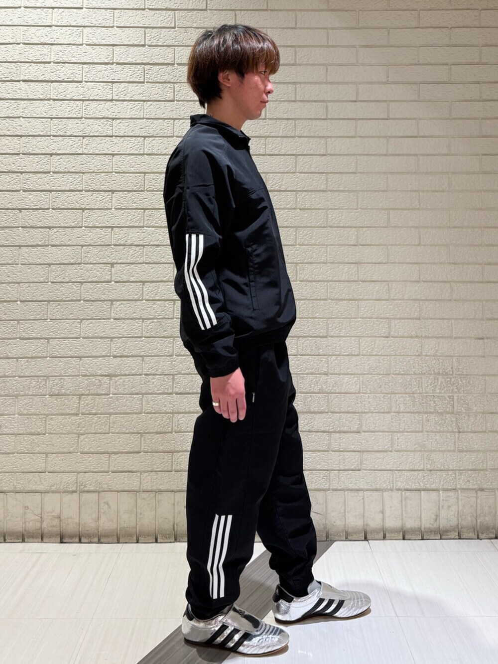 シルバー系のシューズ、ブラック系のパンツ、ブラック系のトップスを着用したメンズの冬コーディネートの2枚目の写真