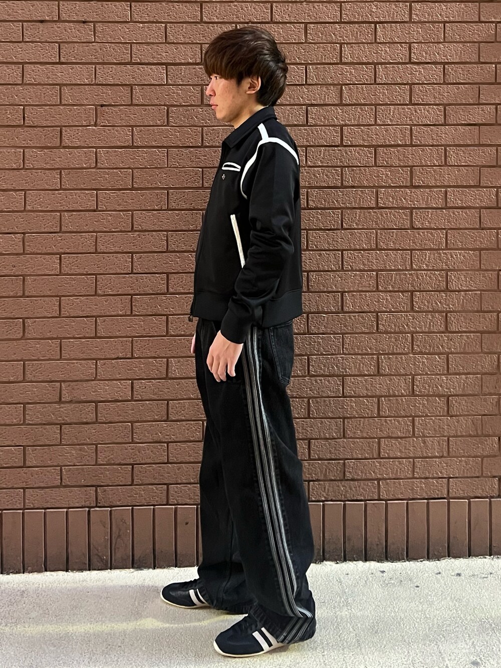 ブラック系のナイロンジャケット、ブラック系のシューズ、ブラック系のデニムパンツを着用したメンズの冬コーディネートの3枚目の写真