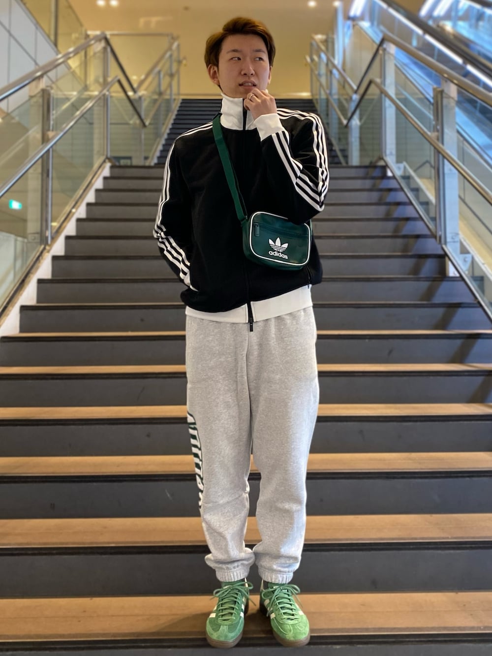 ブラック系のジャージ、グリーン系のショルダーバッグ、グレー系のスウェットパンツを着用したメンズの春コーディネートの2枚目の写真
