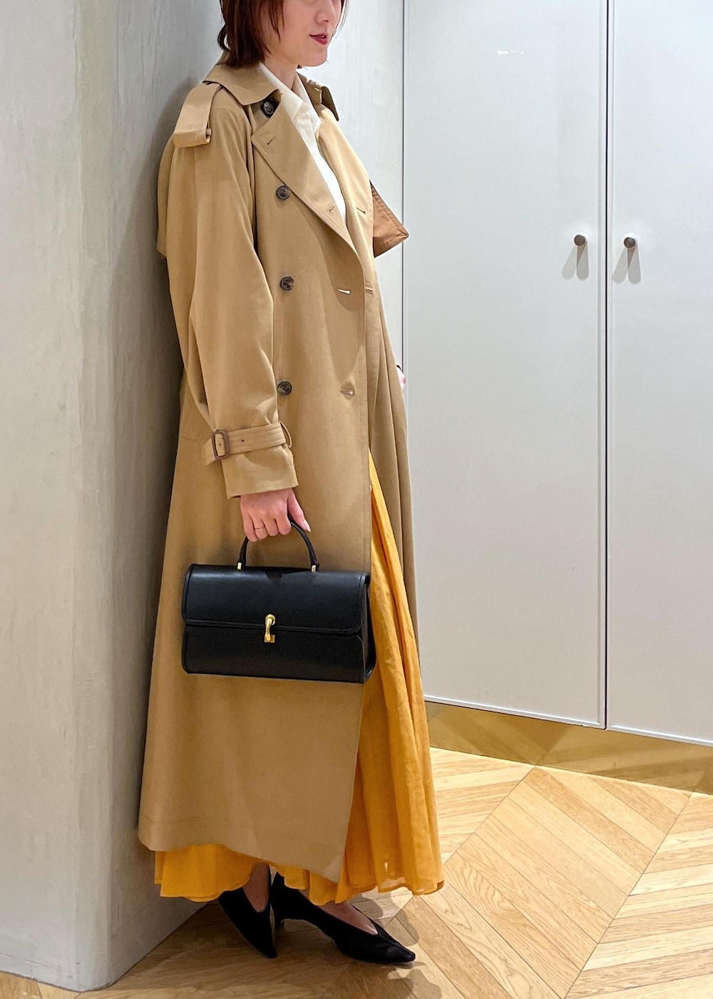 ブラック系のパンプス、オレンジ系のスカート、ホワイト系のシャツ/ブラウスを着用したレディースの春コーディネートの4枚目の写真