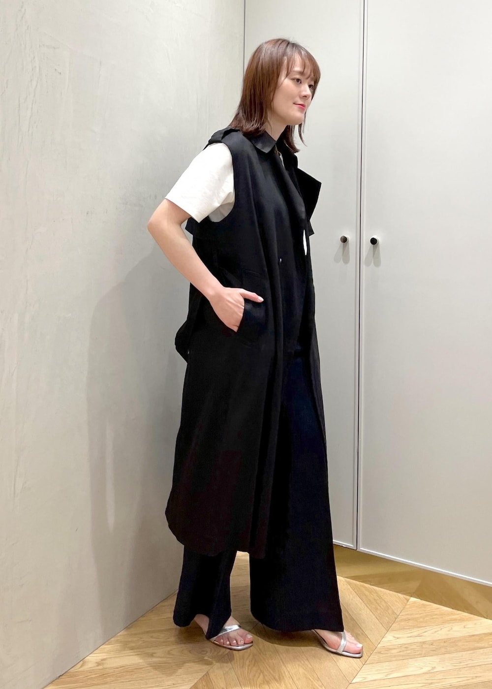 シルバー系のサンダル、ブラック系のハンドバッグ、ブルー系のデニムパンツを着用したレディースの夏コーディネートの2枚目の写真