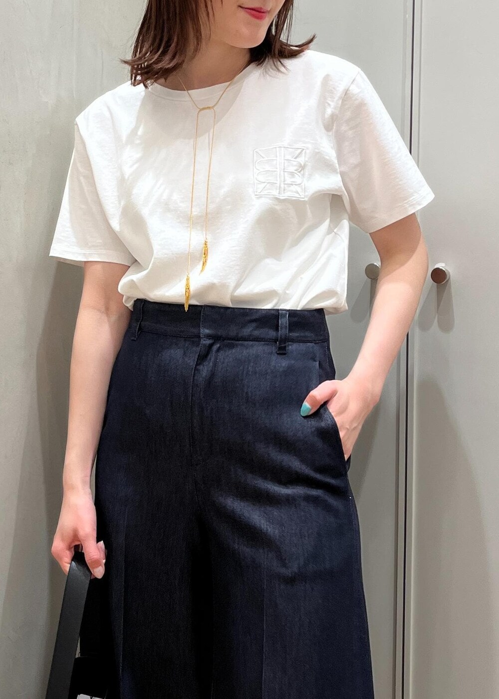 シルバー系のサンダル、ブラック系のハンドバッグ、ブルー系のデニムパンツを着用したレディースの夏コーディネートの6枚目の写真