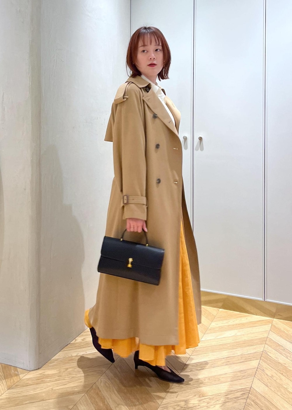 ブラック系のパンプス、オレンジ系のスカート、ホワイト系のシャツ/ブラウスを着用したレディースの春コーディネートの3枚目の写真