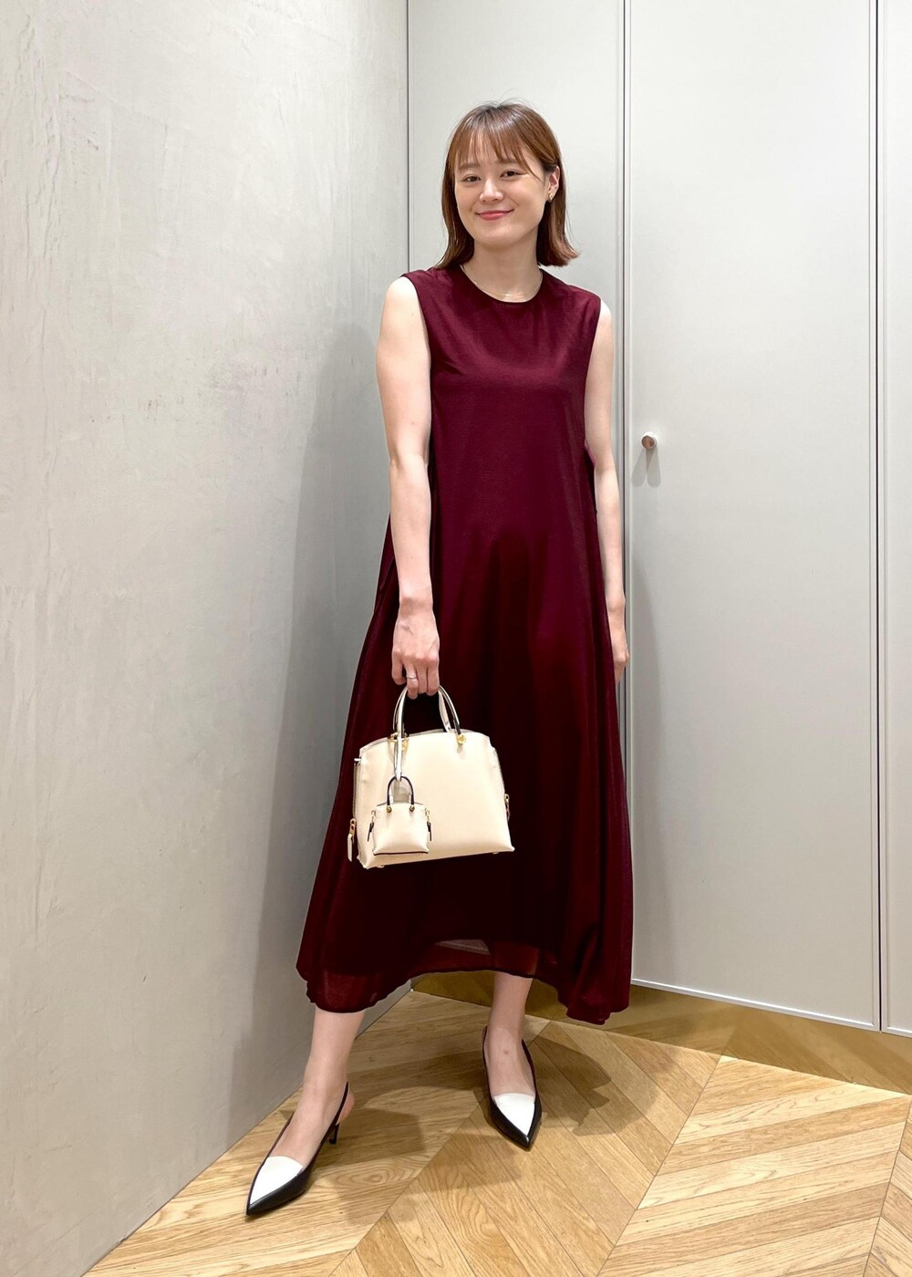 ブラック系のパンプス、レッド系のワンピース、ベージュ系のハンドバッグを着用したレディースの夏コーディネートの4枚目の写真