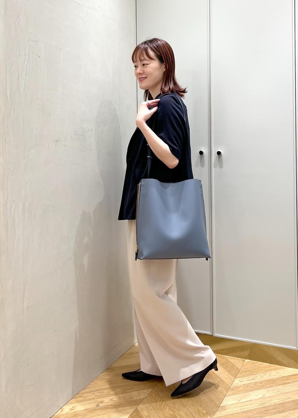 ブルー系のショルダーバッグ、ブラック系のパンプス、ベージュ系のその他パンツを着用したレディースの夏コーディネートの2枚目の写真