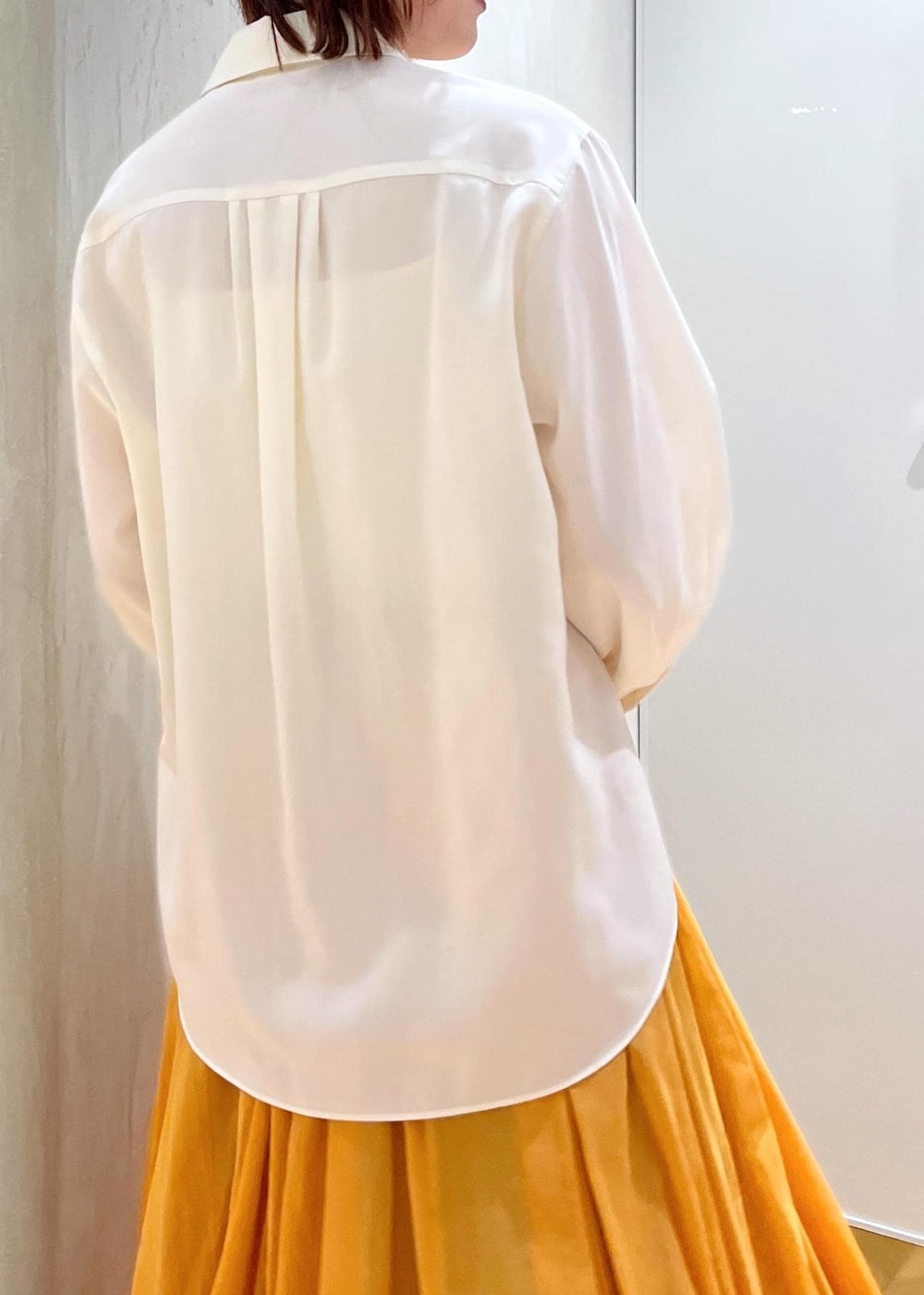 ブラック系のパンプス、オレンジ系のスカート、ホワイト系のシャツ/ブラウスを着用したレディースの春コーディネートの9枚目の写真