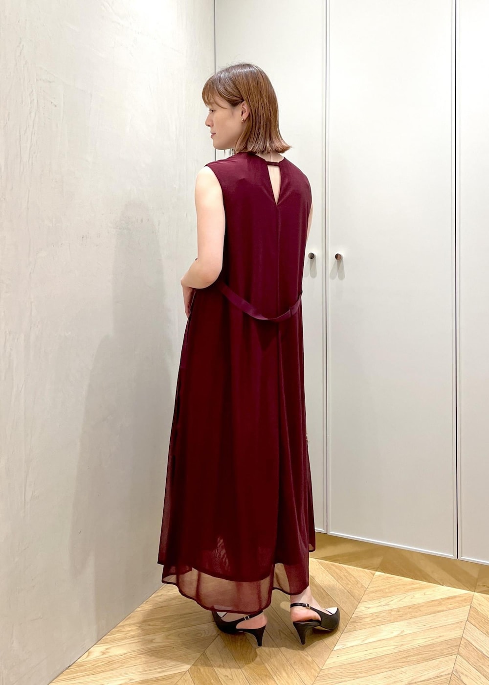 ブラック系のパンプス、レッド系のワンピース、ベージュ系のハンドバッグを着用したレディースの夏コーディネートの3枚目の写真