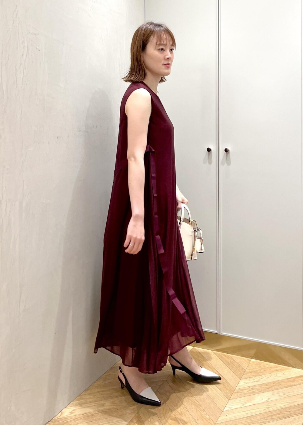 ブラック系のパンプス、レッド系のワンピース、ベージュ系のハンドバッグを着用したレディースの夏コーディネートの2枚目の写真