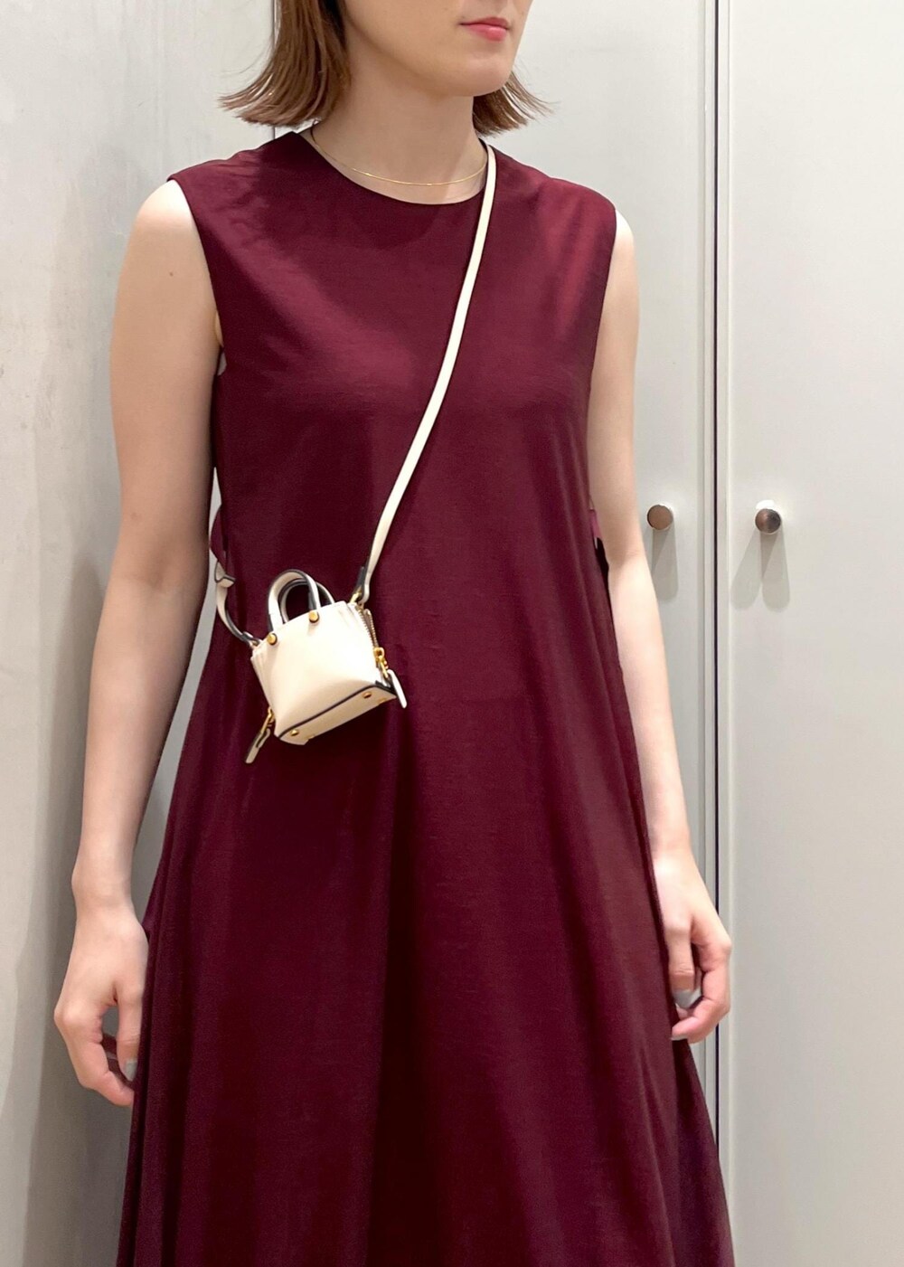 ブラック系のパンプス、レッド系のワンピース、ベージュ系のハンドバッグを着用したレディースの夏コーディネートの7枚目の写真