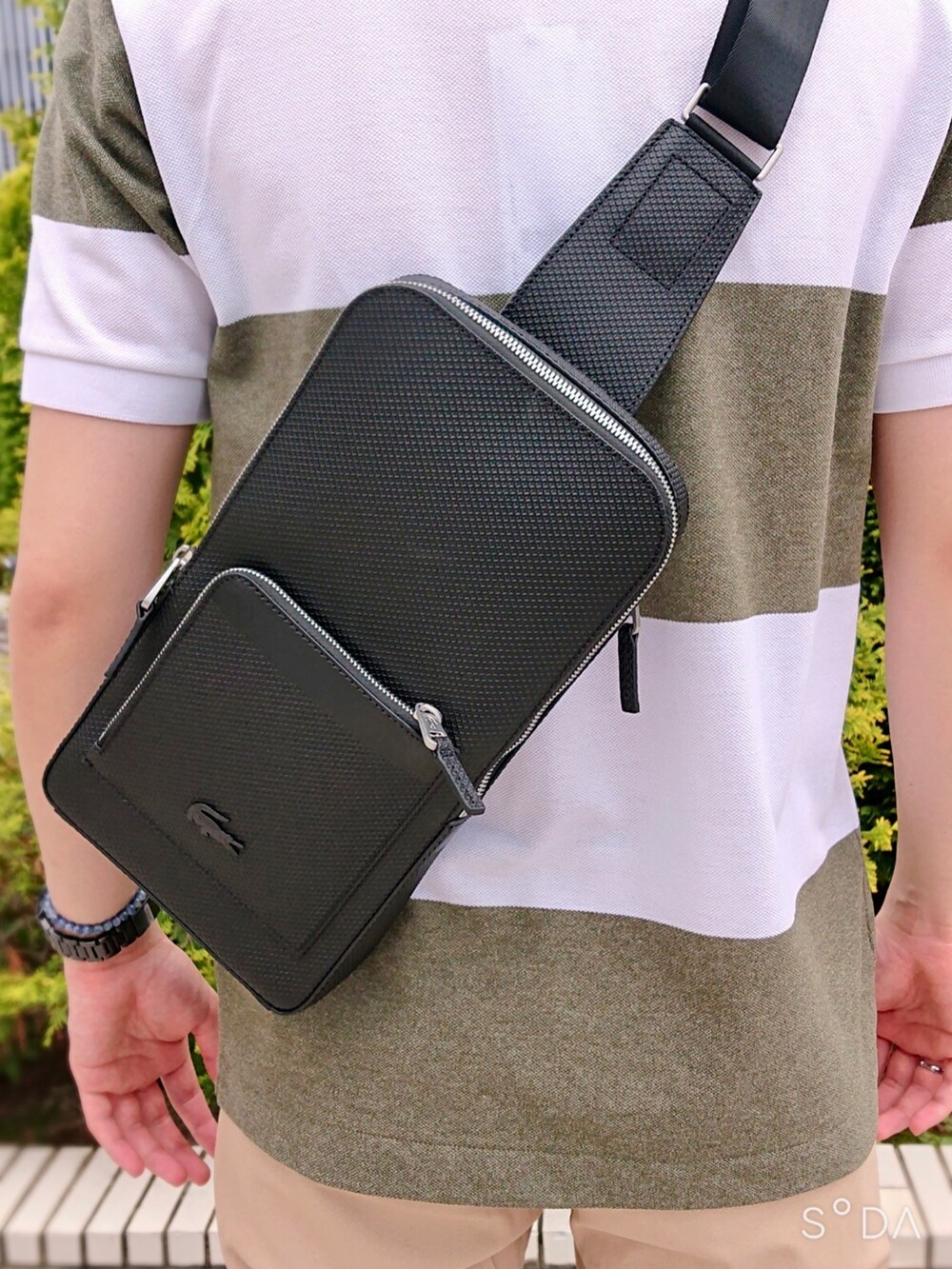 グリーン系のポロシャツ、ベージュ系のスラックス、ホワイト系のスニーカーを着用したメンズの春コーディネートの5枚目の写真