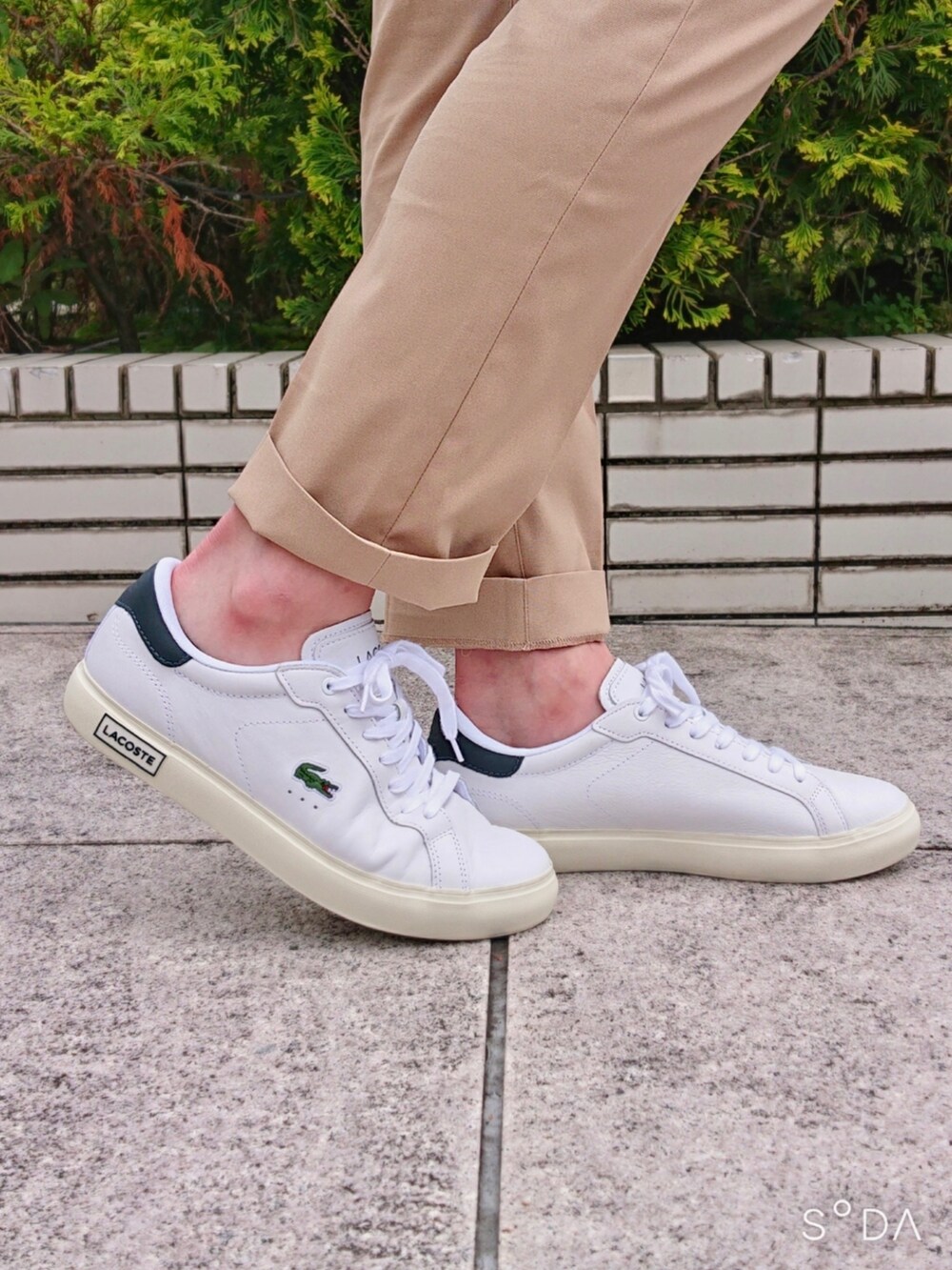 グリーン系のポロシャツ、ベージュ系のスラックス、ホワイト系のスニーカーを着用したメンズの春コーディネートの6枚目の写真