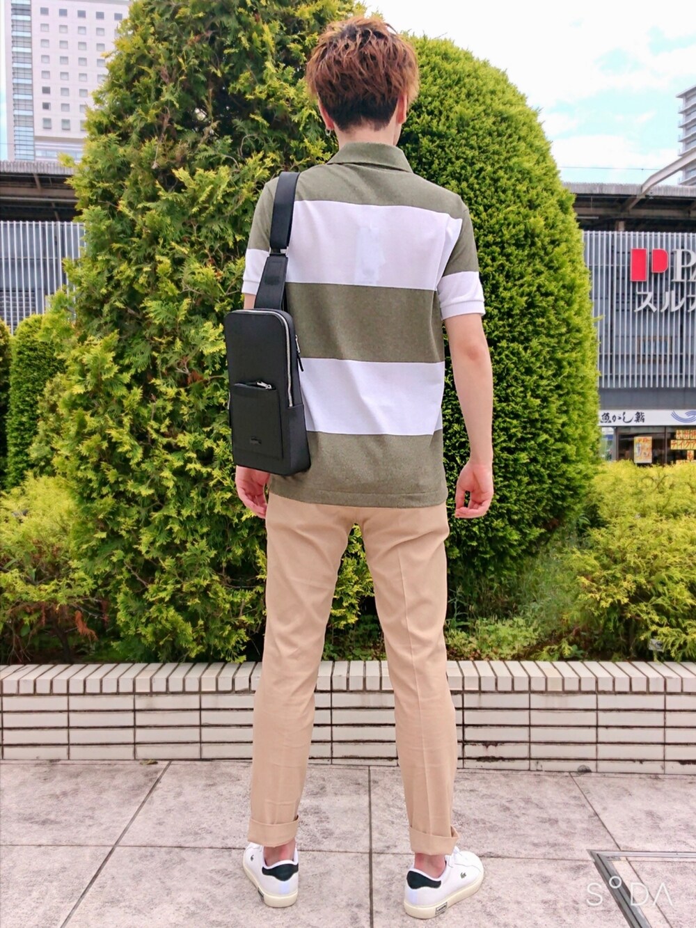 グリーン系のポロシャツ、ベージュ系のスラックス、ホワイト系のスニーカーを着用したメンズの春コーディネートの3枚目の写真