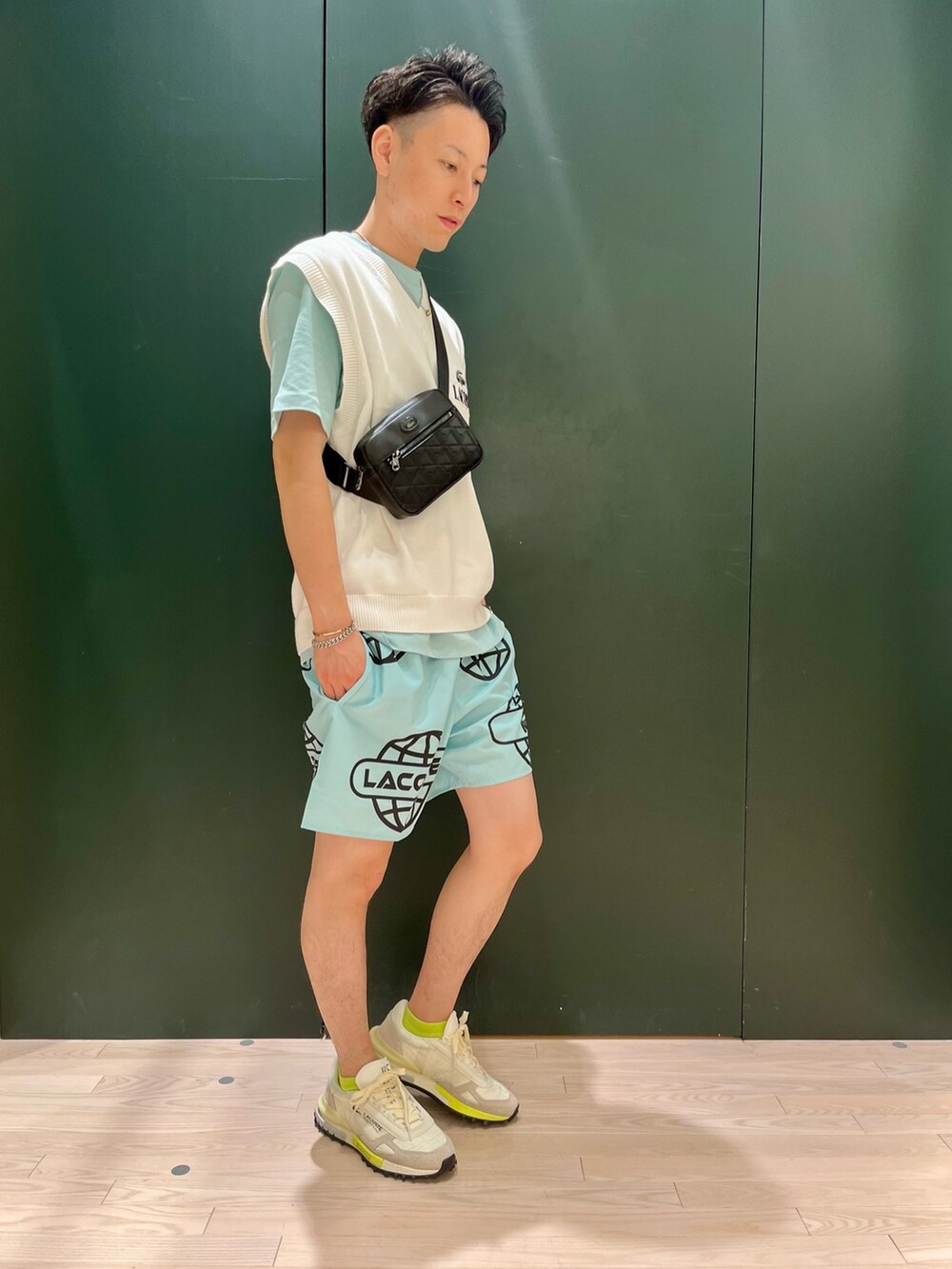 ホワイト系のベスト、ブルー系のTシャツ/カットソー、ホワイト系のスニーカーを着用したメンズの秋コーディネートの2枚目の写真