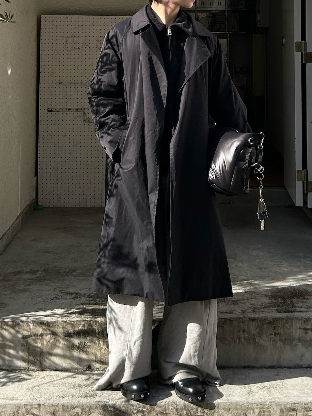 ブラック系のショルダーバッグ、グレー系のスウェットパンツ、ブラック系のブーツを着用したメンズの冬コーディネートの2枚目の写真