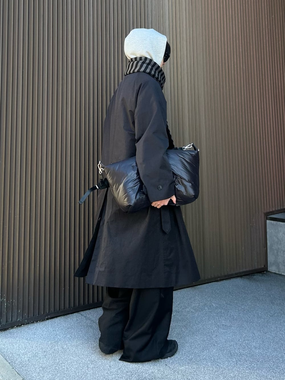 ブラック系のトレンチコート、ブラック系のスラックス、ブラック系のスニーカーを着用したメンズの冬コーディネートの2枚目の写真