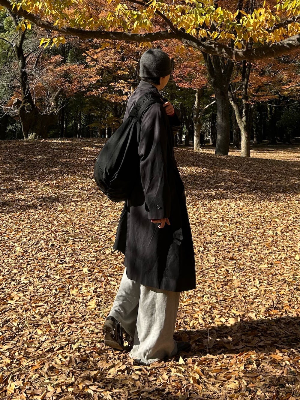 ブラック系のショルダーバッグ、ブラック系のトレンチコート、レッド系のニット/セーターを着用したメンズの秋コーディネートの2枚目の写真