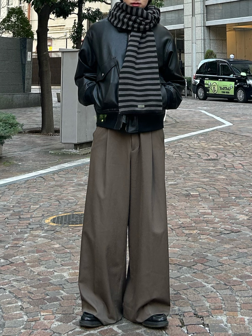 ブラック系のローファー、ブラウン系のスラックス、ブラック系のブルゾンを着用したメンズの冬コーディネートの2枚目の写真