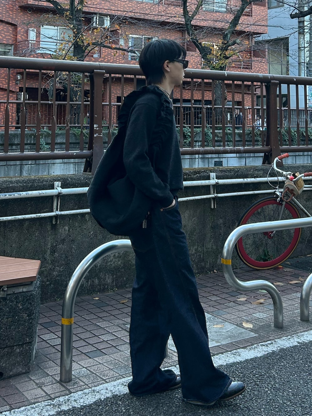 ブルー系のデニムパンツ、グレー系のニット/セーター、ブラック系のショルダーバッグを着用したメンズの冬コーディネートの2枚目の写真