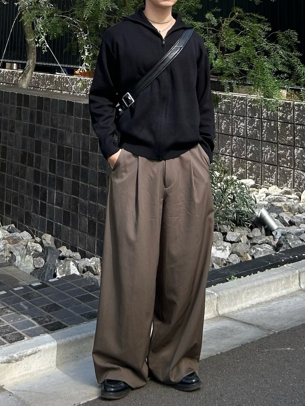 ブラック系のショルダーバッグ、ブラウン系のスラックス、ブラック系のニット/セーターを着用したメンズの秋コーディネートの2枚目の写真