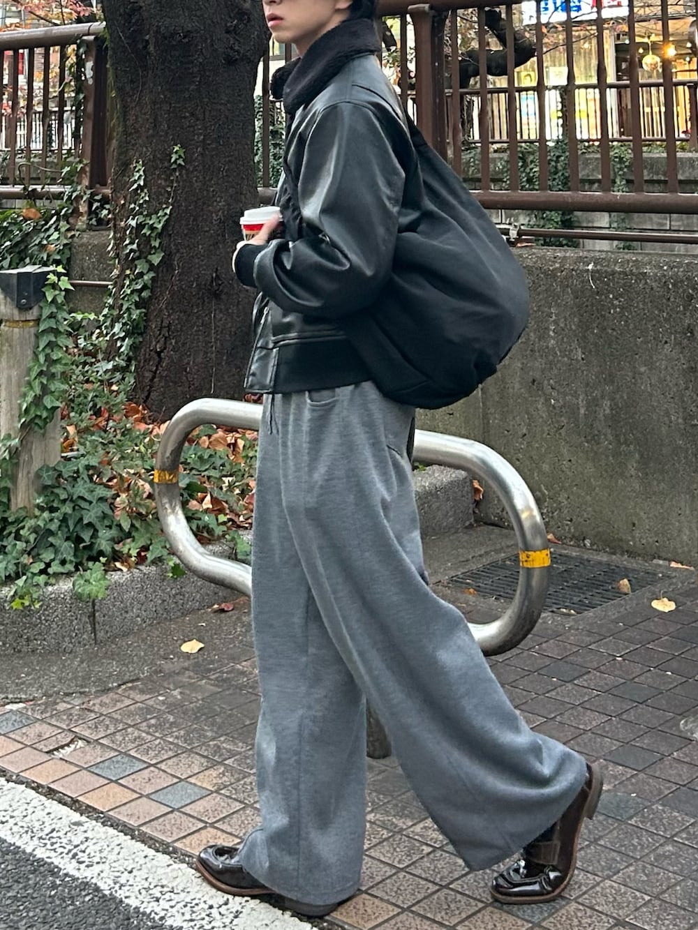 ブラック系のショルダーバッグ、ブラック系のブルゾン、グレー系のスウェットパンツを着用したメンズの冬コーディネートの2枚目の写真