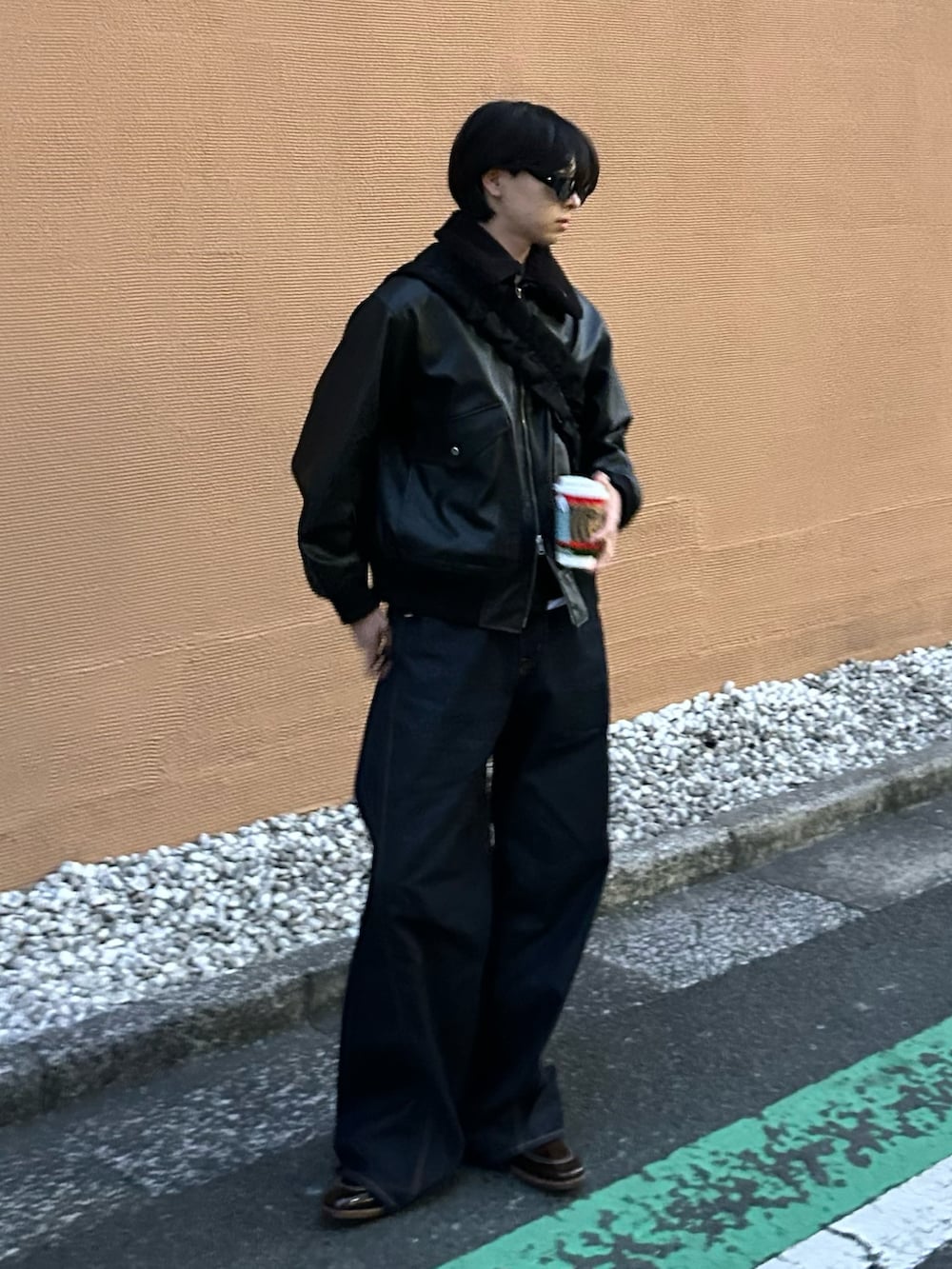 ブルー系のデニムパンツ、ブラック系のショルダーバッグ、ブラック系のブルゾンを着用したメンズの冬コーディネートの2枚目の写真