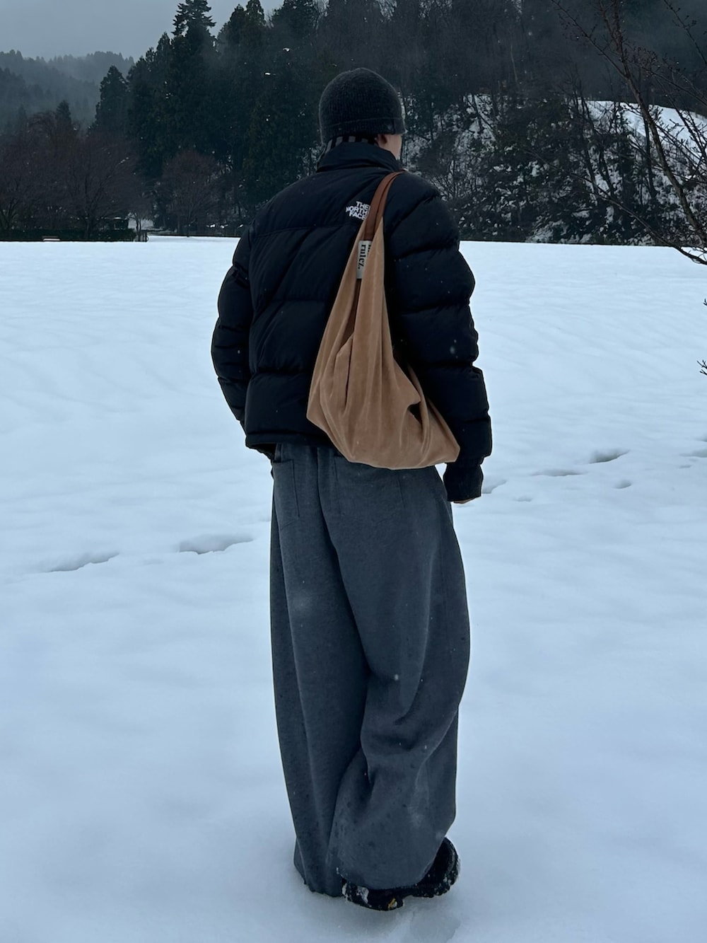 ブラック系のスニーカー、グレー系のスウェットパンツ、ブラック系のダウンジャケット/コートを着用したメンズの冬コーディネートの2枚目の写真