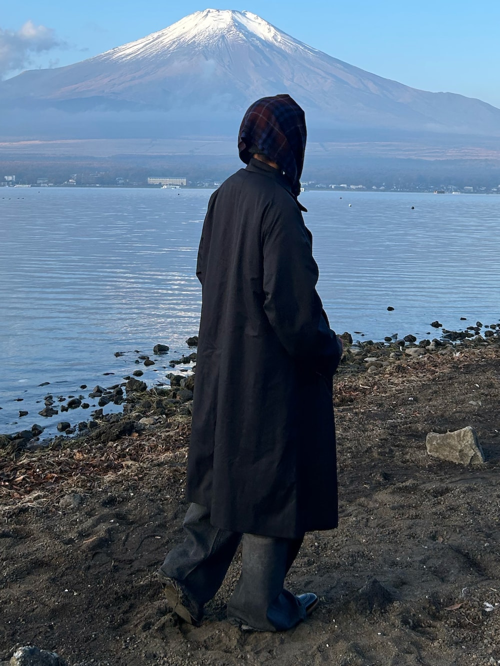 ブラック系のトレンチコート、ブラック系のデニムパンツ、ブラウン系のローファーを着用したメンズの秋コーディネートの2枚目の写真