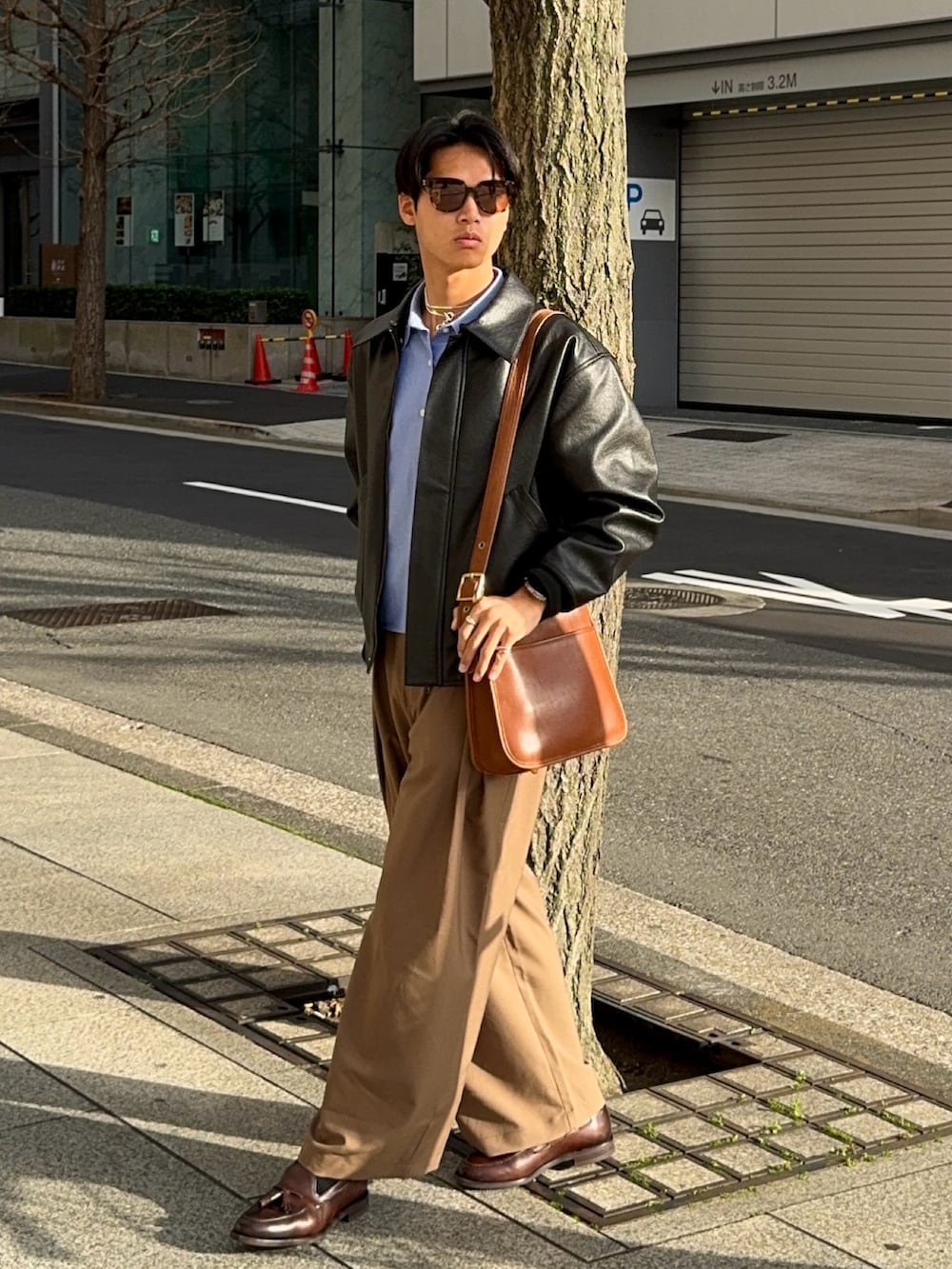 ブラウン系のスラックス、ブラウン系のローファー、ブラック系のその他アウターを着用したメンズの春コーディネートの3枚目の写真