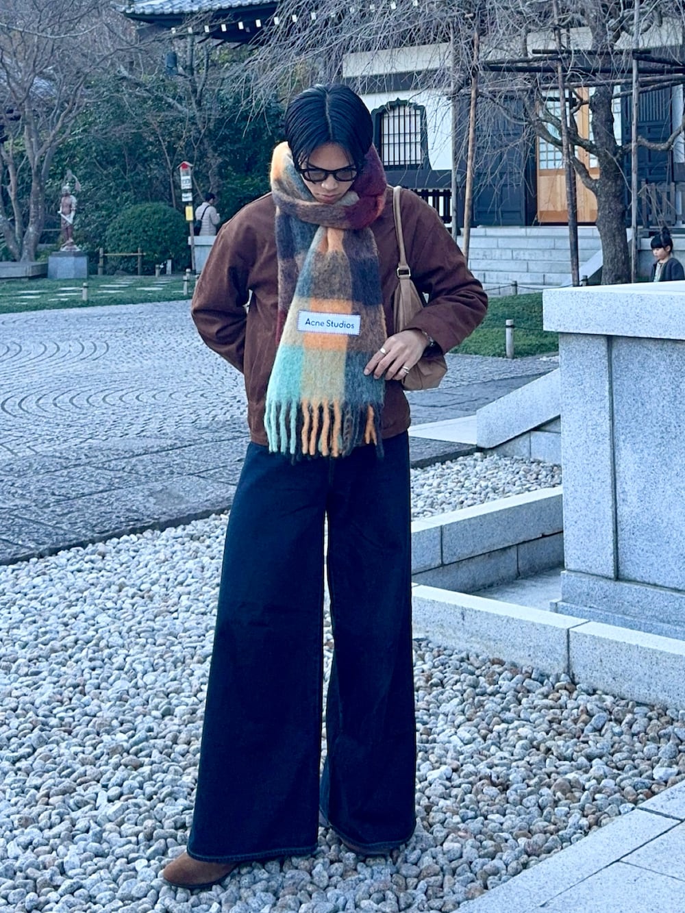 ブラウン系のブルゾン、ブルー系のデニムパンツ、ベージュ系のショルダーバッグを着用したメンズの冬コーディネートの5枚目の写真