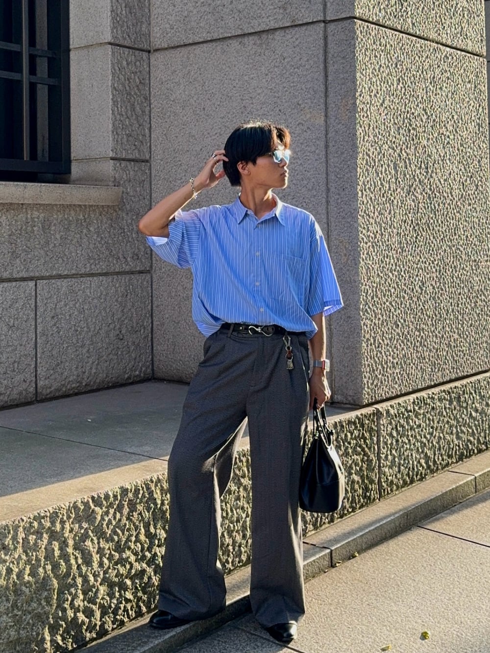 グレー系のスラックス、ブラック系のバッグ、ブルー系のシャツ/ブラウスを着用したメンズの夏コーディネートの5枚目の写真