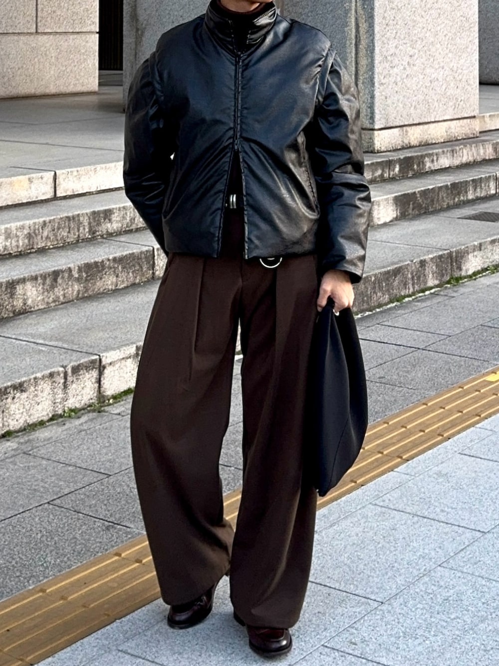 ブラック系のダウンジャケット/コート、ブラック系のハンドバッグ、ブラウン系のローファーを着用したメンズの冬コーディネートの4枚目の写真