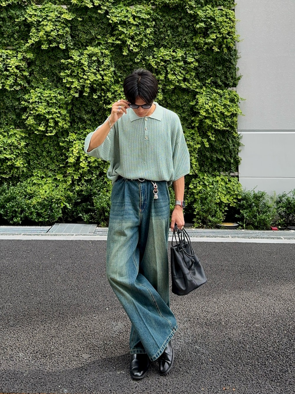 ブルー系のデニムパンツ、ブラック系のバッグ、グリーン系のポロシャツを着用したメンズの夏コーディネートの3枚目の写真