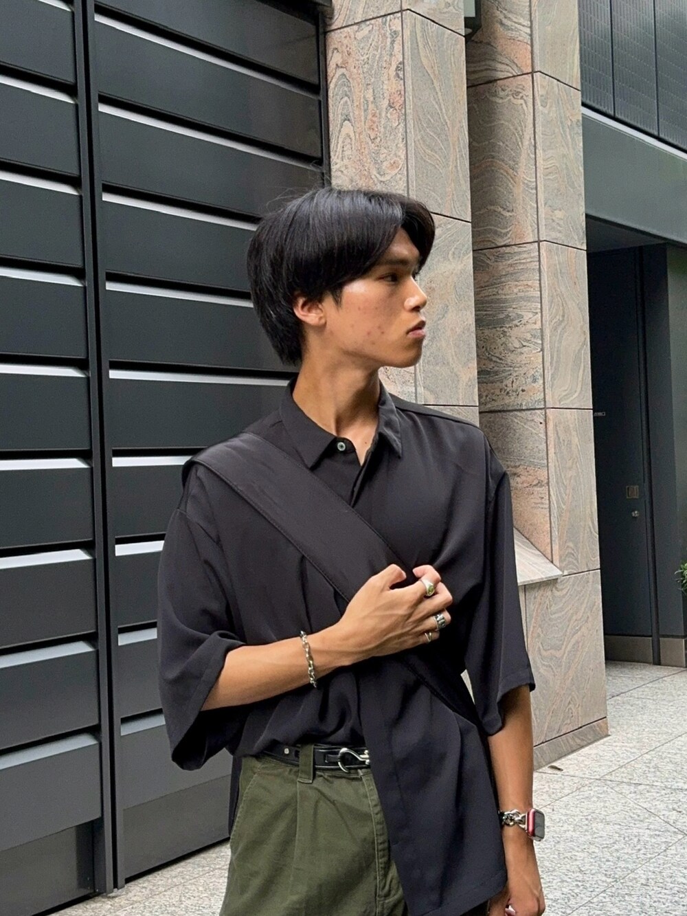 グリーン系のカーゴパンツ、ベージュ系のモカシン/デッキシューズ、ブラック系のシャツ/ブラウスを着用したメンズの夏コーディネートの2枚目の写真