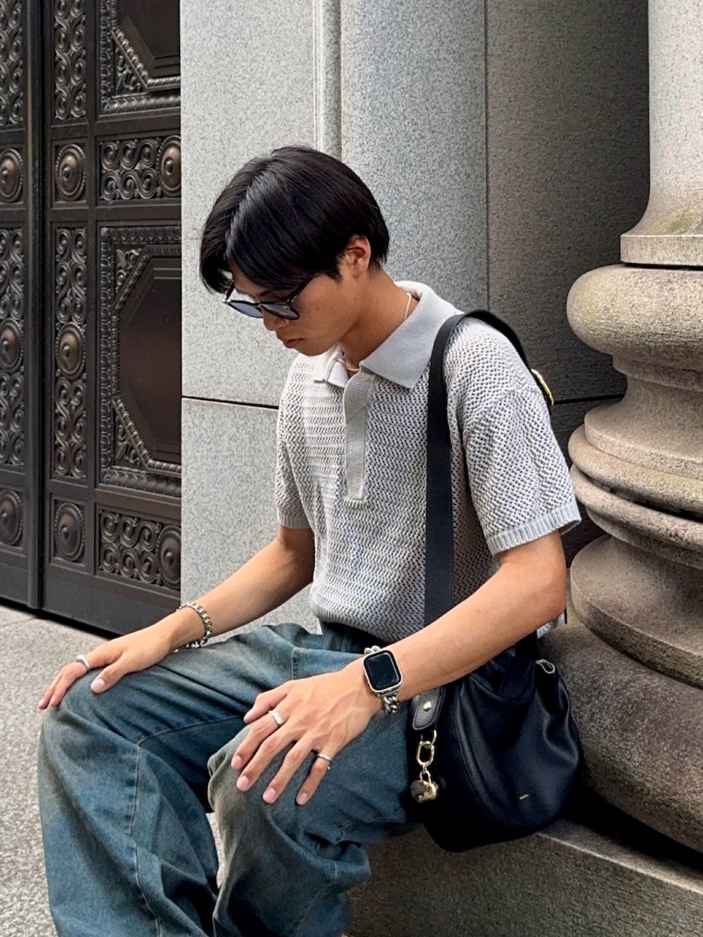 ブルー系のデニムパンツ、ブラック系のハンドバッグ、ブラック系のドレスシューズを着用したメンズの夏コーディネートの2枚目の写真