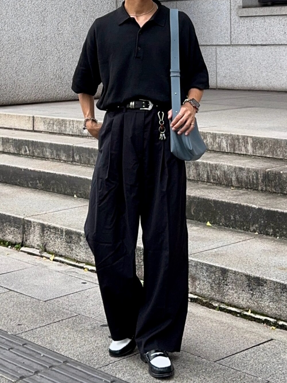 ブラック系のローファー、ブラック系のポロシャツ、ブルー系のショルダーバッグを着用したメンズの夏コーディネートの4枚目の写真